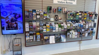 Chautauqua County Visitors Bureau travel guides in rack and on tv screen