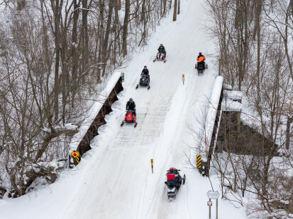 Snowmobilers crossing bridge on Rails to Trails