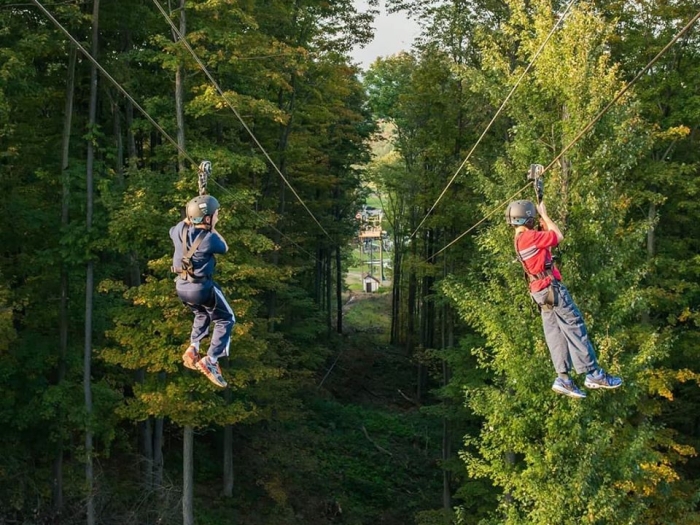 Two people on the zipline at Peek'n Peak Resort