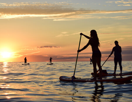 People standup paddleboarding at sunset on Lake Erie's Sunset Bay, NY