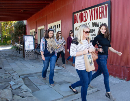 A group of female friends leave a winery with purchases in hand.