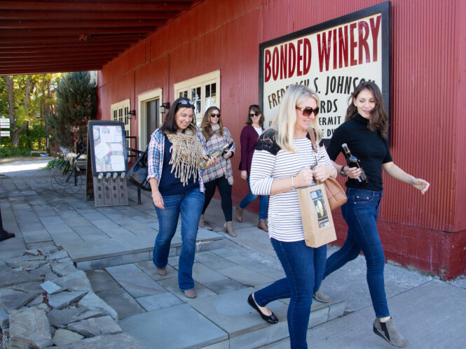 A group of female friends leave a winery with purchases in hand.
